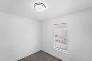 Spare room featuring dark colored carpet, crown molding, and a textured ceiling