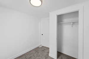 Unfurnished bedroom with dark carpet, a closet, and a textured ceiling