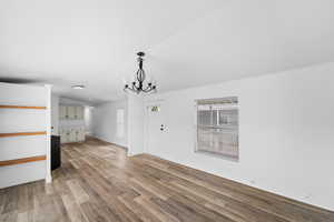 Unfurnished dining area featuring suspended lighting, light wood-style floors, and vaulted ceiling