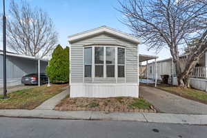 Manufactured / mobile home featuring an attached carport and asphalt driveway