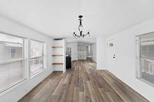 Unfurnished living room featuring a chandelier, dark wood-style floors, and crown molding