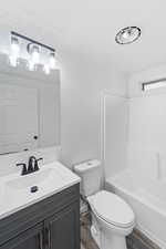Bathroom with vanity, dark wood finished floors, shower / bathtub combination, and a textured ceiling