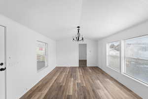 Unfurnished dining area featuring hanging lights, lofted ceiling, and light wood finished floors