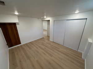Unfurnished bedroom featuring a textured ceiling, light wood finished floors, a closet, and recessed lighting