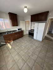 Kitchen featuring stainless steel appliances, light tile patterned flooring, dark wood finish cabinetry, and decorative backsplash