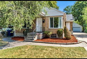 View of front of home featuring brick siding, an outdoor structure, a garage, and a front yard