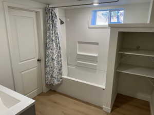 Full bath featuring light wood-type flooring, vanity, shower / tub combo, and a closet