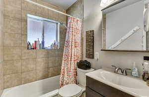 Bathroom featuring a textured wall, vanity, and shower / tub combo