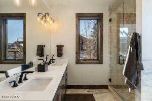 Full bath featuring double vanity and a stall shower
