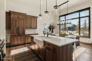Kitchen featuring pendant lighting, a kitchen breakfast bar, light countertops, a center island with sink, and dark wood-type flooring