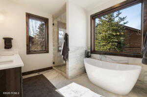 Bathroom with double vanity, a stall shower, and a soaking tub