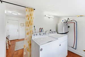 Laundry area with dark wood finished floors, independent washer and dryer, a textured ceiling, and water heater