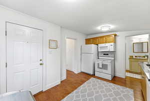 Kitchen with white appliances, light wood-style floors, light countertops, ornamental molding, and wood finish cabinetry