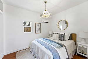 Bedroom with dark wood-style floors, a mini split for heating / cooling, and a chandelier