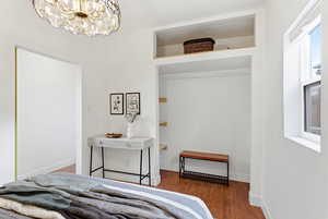 Bedroom with light wood-style floors and suspended lighting