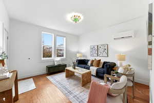 Living room with wood finished floors and a wall mounted mini split