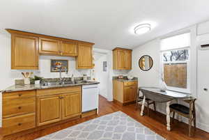 Kitchen with dark wood-style floors, white dishwasher, light stone countertops, and wood finish cabinets