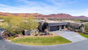 Contemporary house with stone siding, a mountain view, an attached garage, driveway, and a front lawn