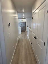 Corridor featuring light wood-style flooring and baseboards