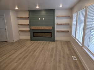 Unfurnished living room with a fireplace and light wood-type flooring