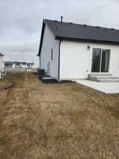 Back of house with a lawn, stucco siding, roof with shingles, a patio area, and entry steps