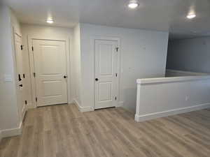 Hall with light wood finished floors and recessed lighting