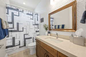 Full bath with vanity, curtained shower, and light wood-type flooring