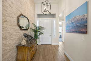 Entryway featuring light wood-style flooring, hanging lights, and a high ceiling