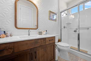 Bathroom featuring wallpapered walls, vanity, and a shower stall