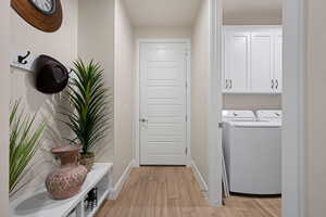 Laundry room with cabinet space, light wood-type flooring, and independent washer and dryer