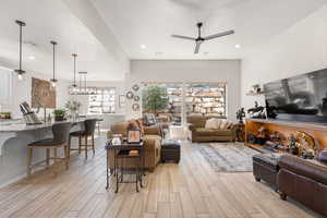 Living room with a ceiling fan, light wood-style flooring, recessed lighting, and a textured ceiling