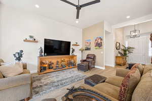 Living room featuring light wood-type flooring, a ceiling fan, and hanging lights