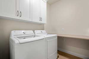 Laundry room featuring cabinet space, separate washer and dryer, and light wood-style floors