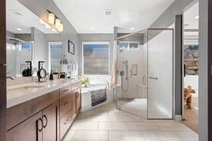 Full bath with a bath, double vanity, a shower stall, and healthy amount of natural light