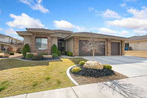 Prairie-style house featuring a front yard, a garage, concrete driveway, stucco siding, and stone siding