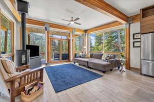 Family/great room area featuring floor to ceiling windows, beamed ceiling, and a wood stove