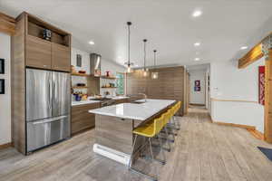Kitchen with open shelves, stainless steel appliances, large island, and modern cabinets