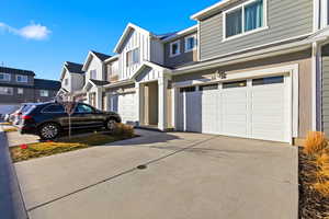 View of side of home featuring board and batten siding, a garage, concrete driveway, and a residential view