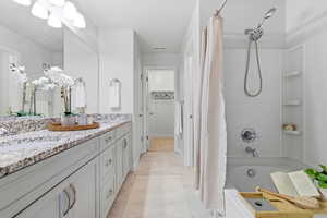 Bathroom with shower / bath combination with curtain, double vanity, and a spacious closet