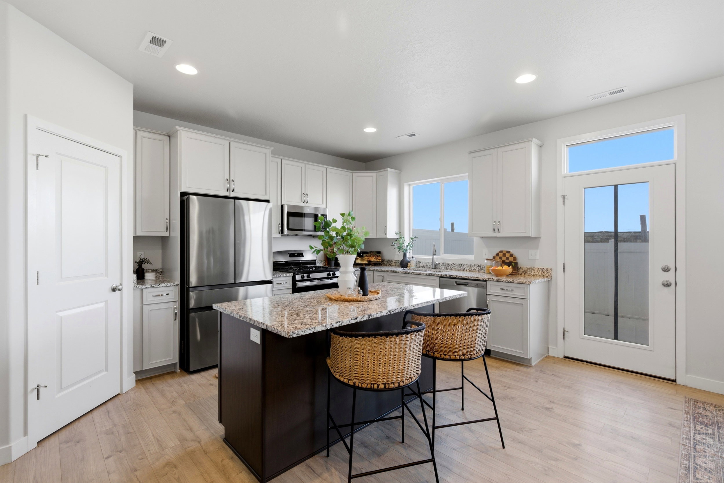 Kitchen with light stone countertops, a kitchen bar, stainless steel appliances, a center island, and light wood-type flooring