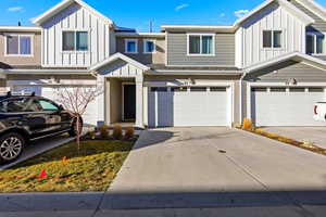 View of front of home with board and batten siding, an attached garage, and driveway
