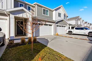 View of front of house with board and batten siding, a garage, concrete driveway, and a residential view