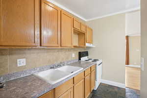 Kitchen featuring slate stone tile floors, crown molding, and tasteful backsplash