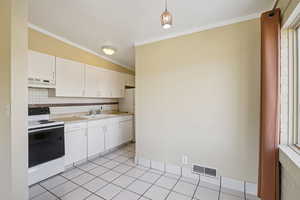 Kitchen featuring range with electric cooktop, light countertops, crown molding, white cabinetry, and backsplash