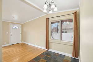 Foyer with ornamental molding, stone finish floors, plenty of natural light, and hanging lights