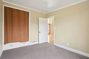 Unfurnished bedroom with light carpet, crown molding, and a closet