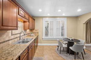 Kitchen with recessed lighting, a textured ceiling, wood finish cabinetry, decorative backsplash, and light tile patterned flooring