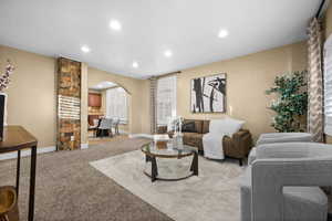 Living room featuring arched walkways, light colored carpet, and recessed lighting