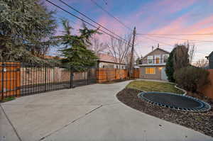 Patio terrace at dusk featuring a fenced backyard, a patio area, and a trampoline