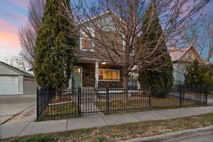 Obstructed view of property featuring covered porch, a fenced front yard, a gate, a garage, and an outdoor structure